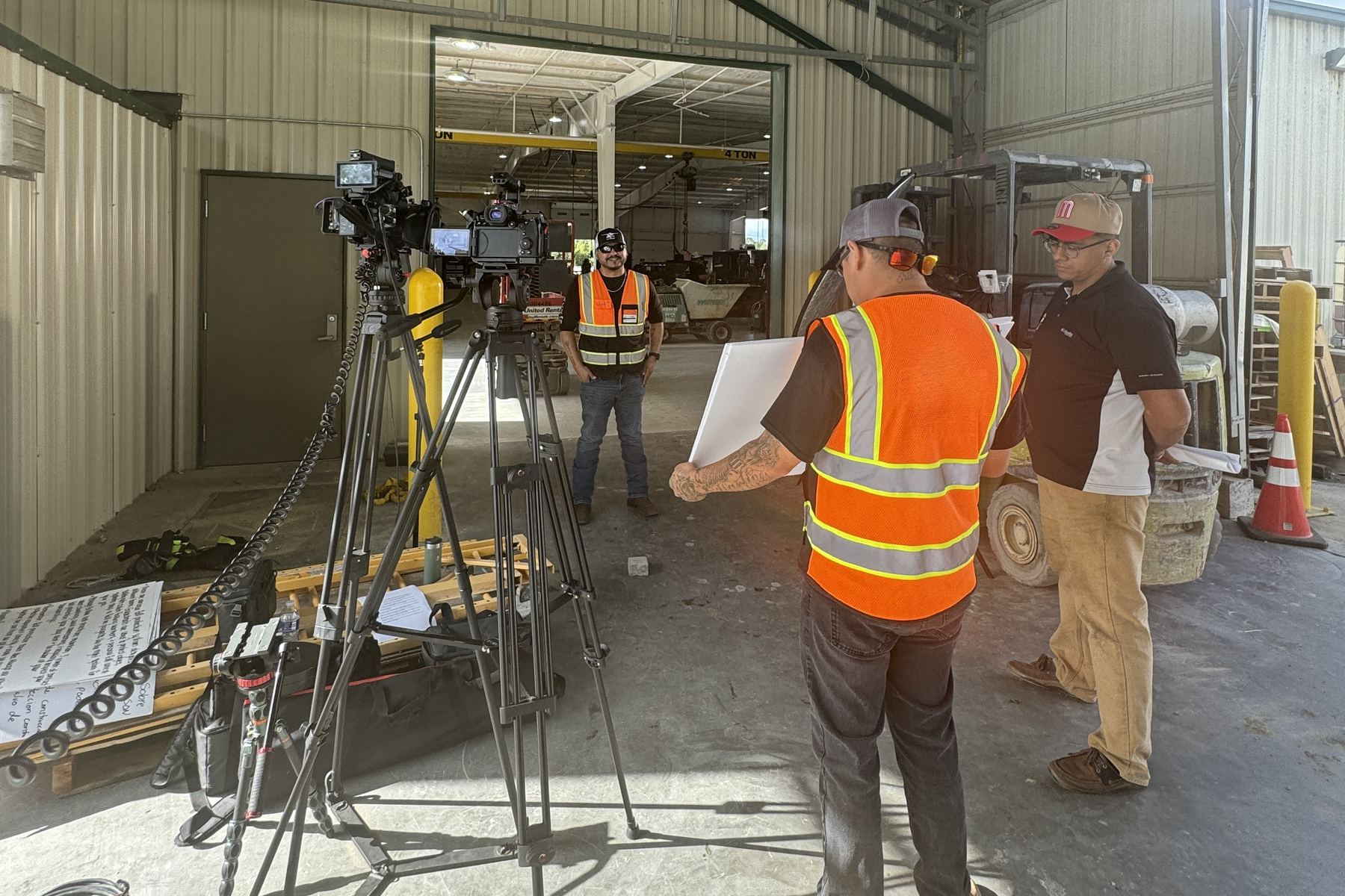 Our crew filming workers in orange safety vests inside a metal shop building