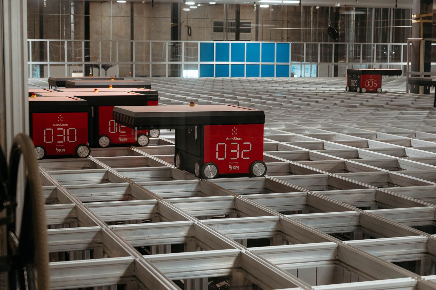 Red AutoStore robots numbered 030 and 032 on the storage grid