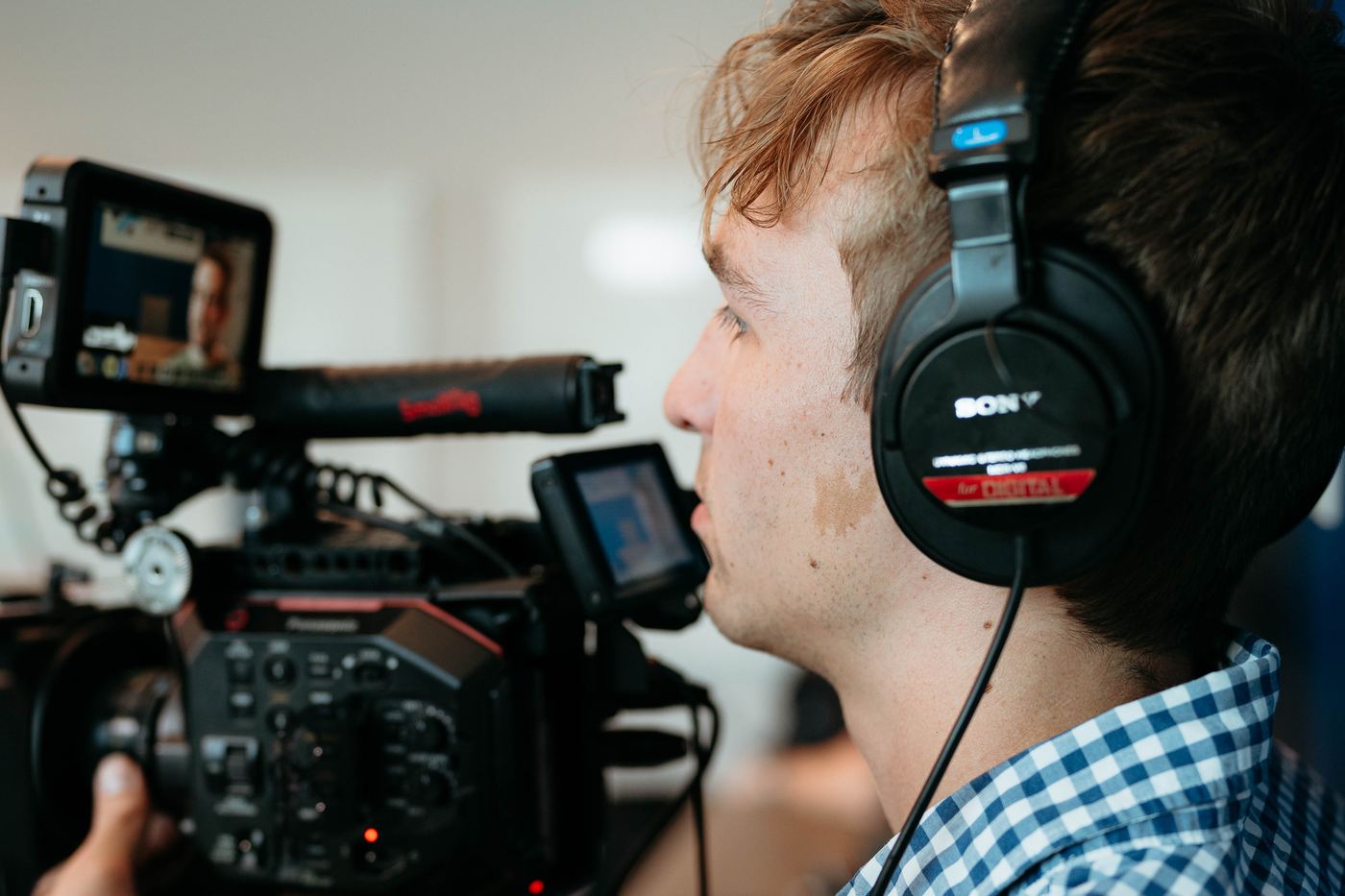 Camera operator in headphones close beside the camera