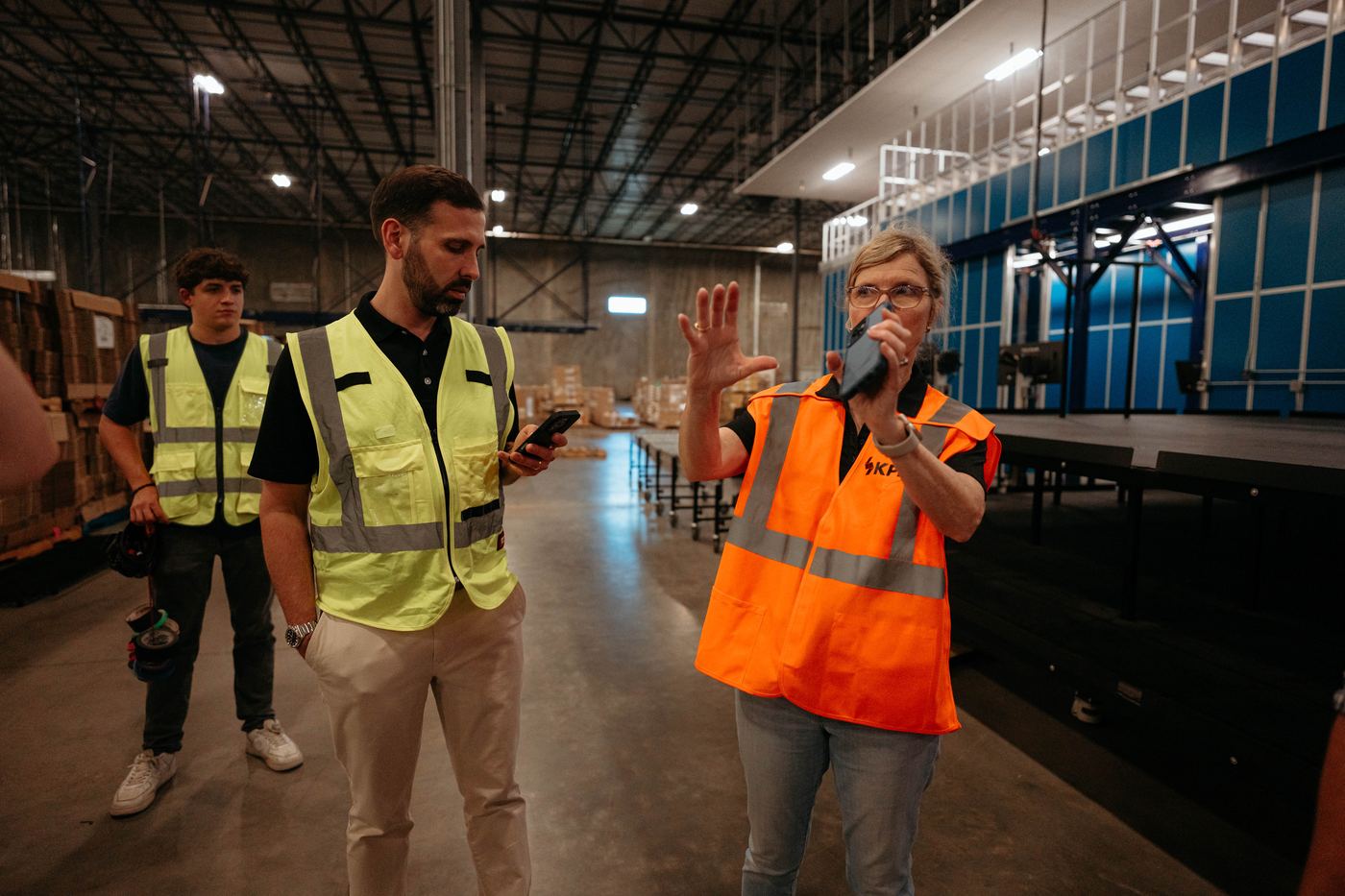 A client in an orange vest walking the crew through a warehouse