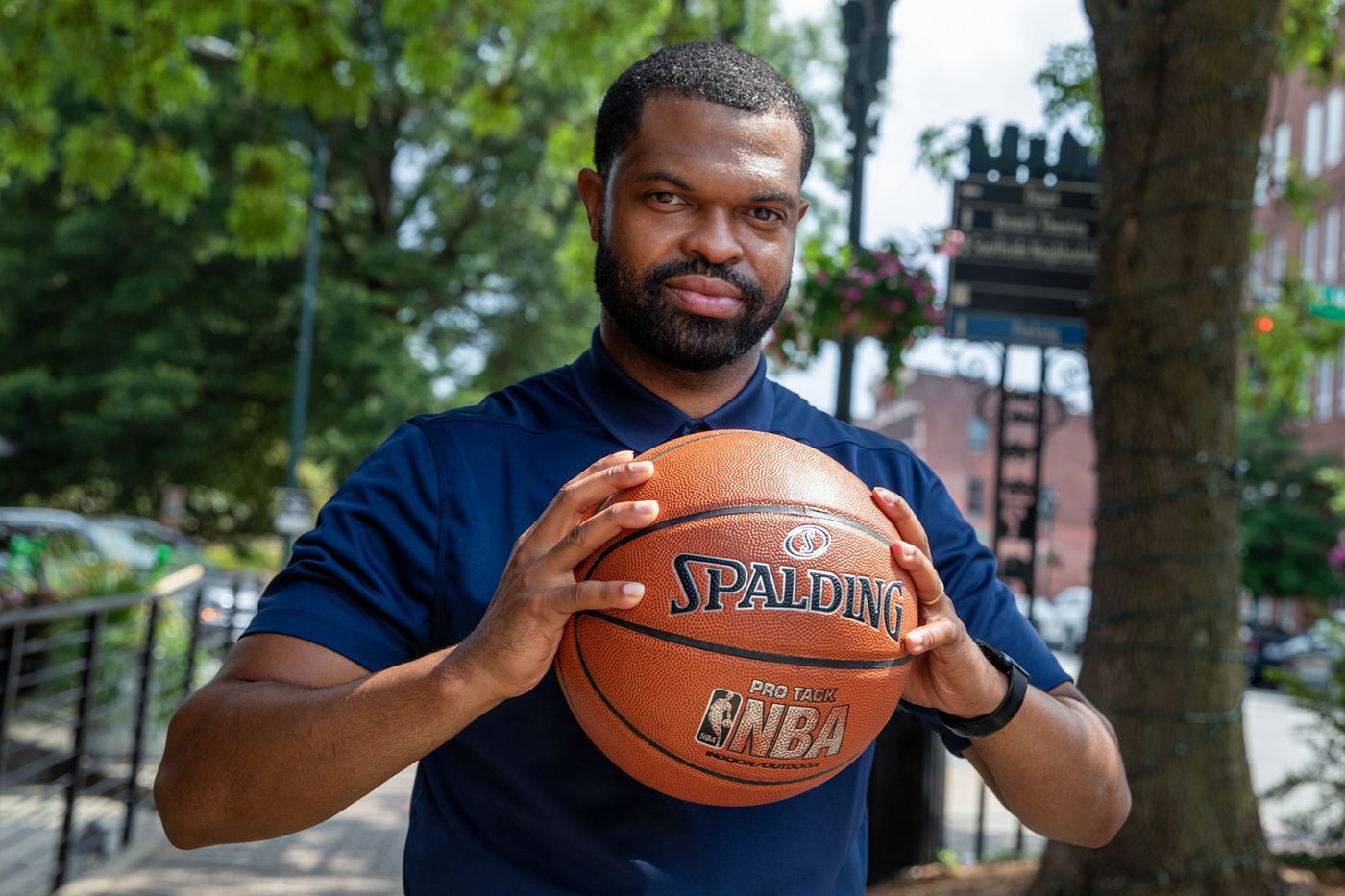 Basketball coach holding a ball in both hands on a downtown sidewalk
