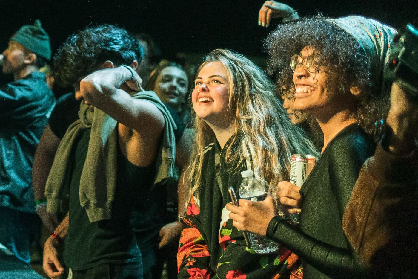 Young woman smiling in a crowd at a concert, friends dancing around her