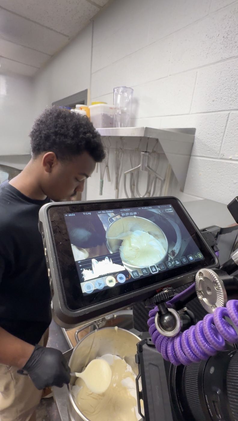 Filming a cook over a pot, the shot on a monitor rig in the foreground