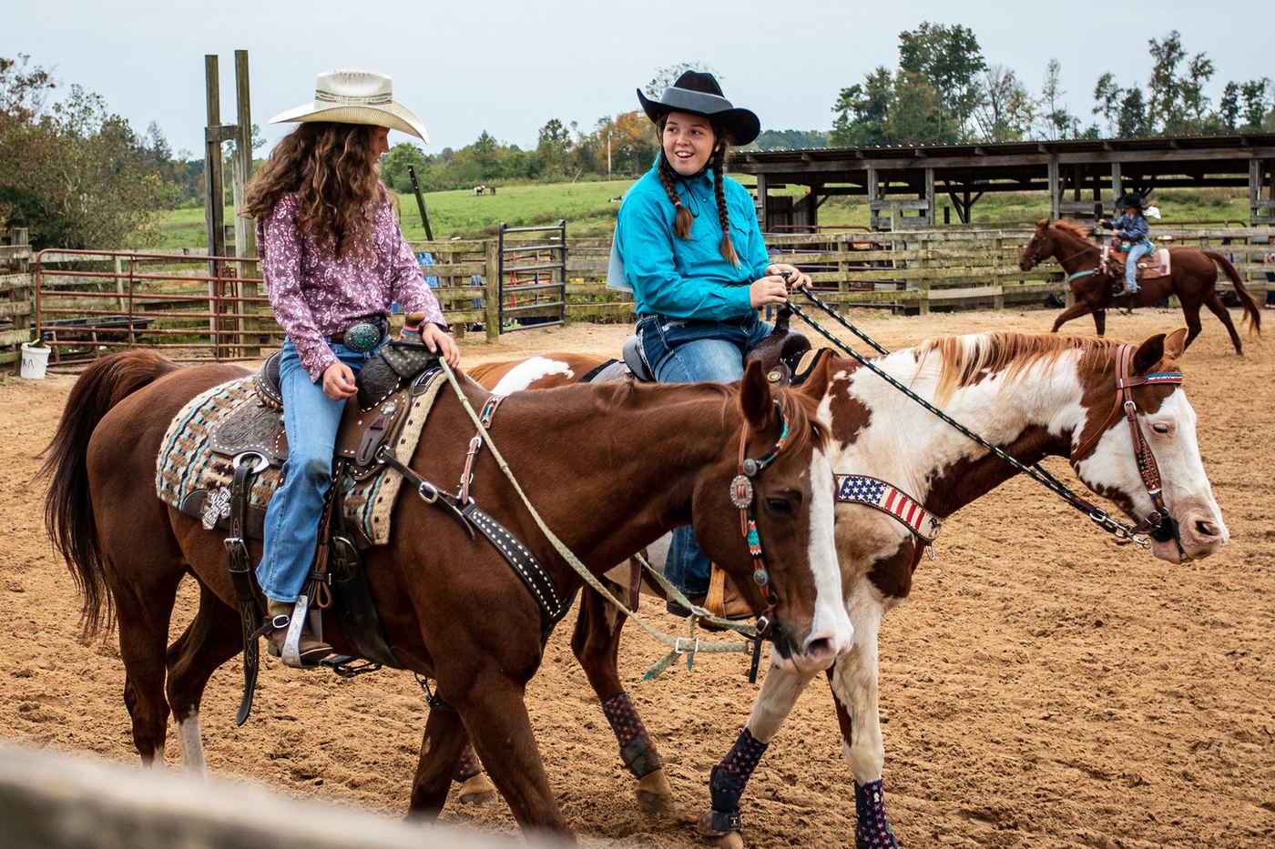 Two young riders in cowboy hats on horseback in a rodeo arena
