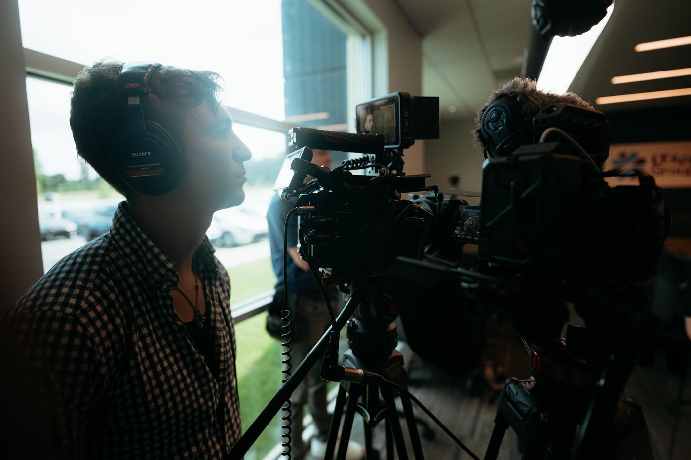 Camera operator in headphones behind two cameras during an interview