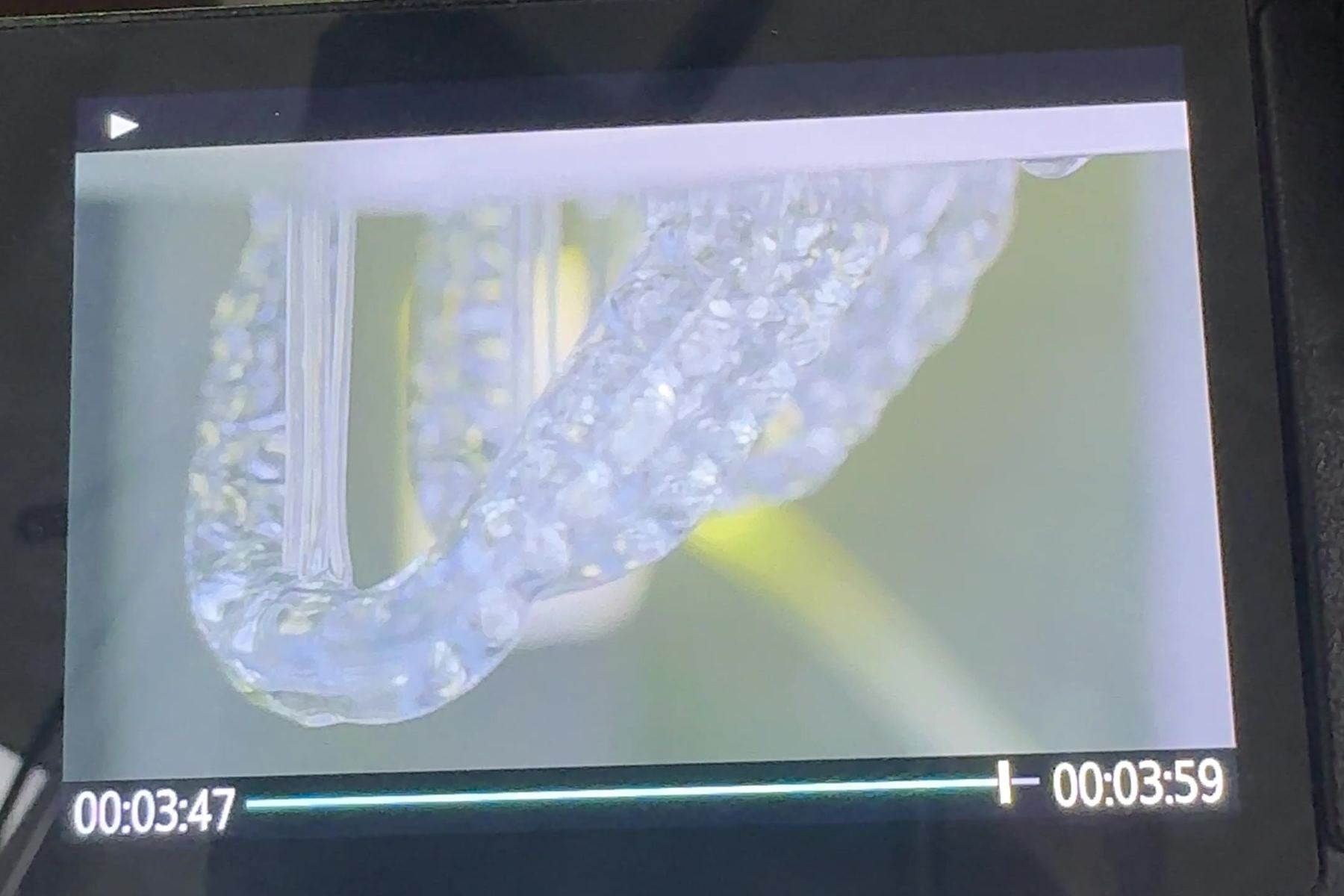 A camera monitor showing a clear 3D printed mouth guard up close during a dental lab shoot