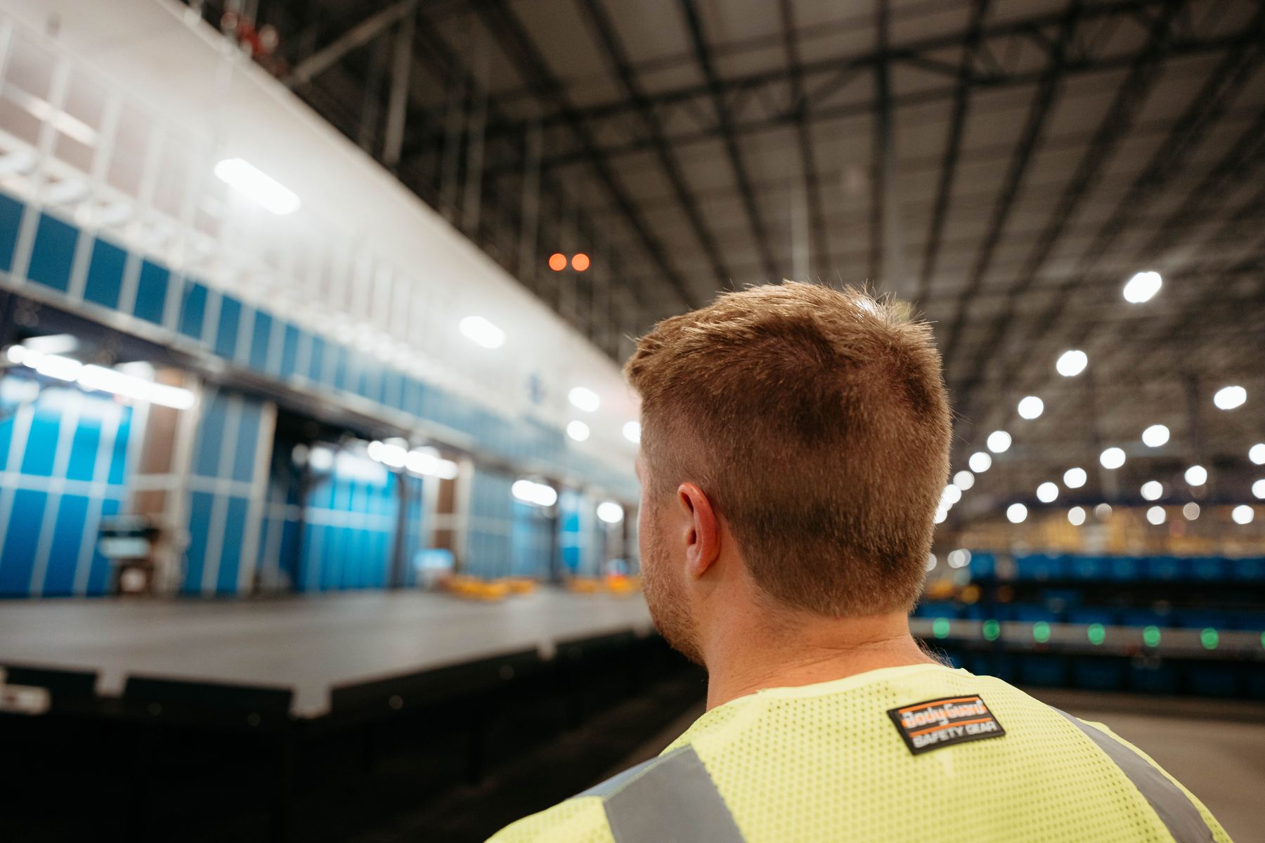 Over the shoulder of our crew member in a safety vest, looking down a quiet warehouse floor
