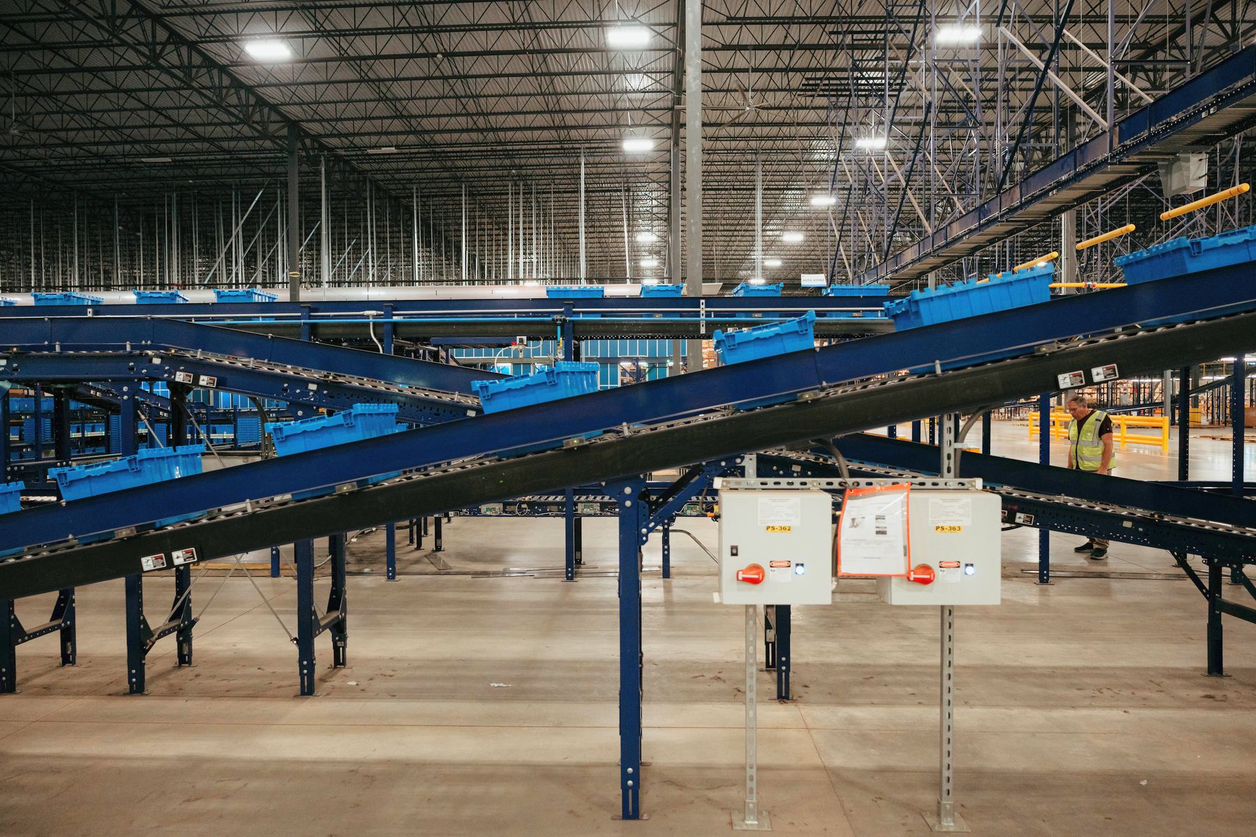 Inclined conveyors carrying blue totes across a large distribution center floor