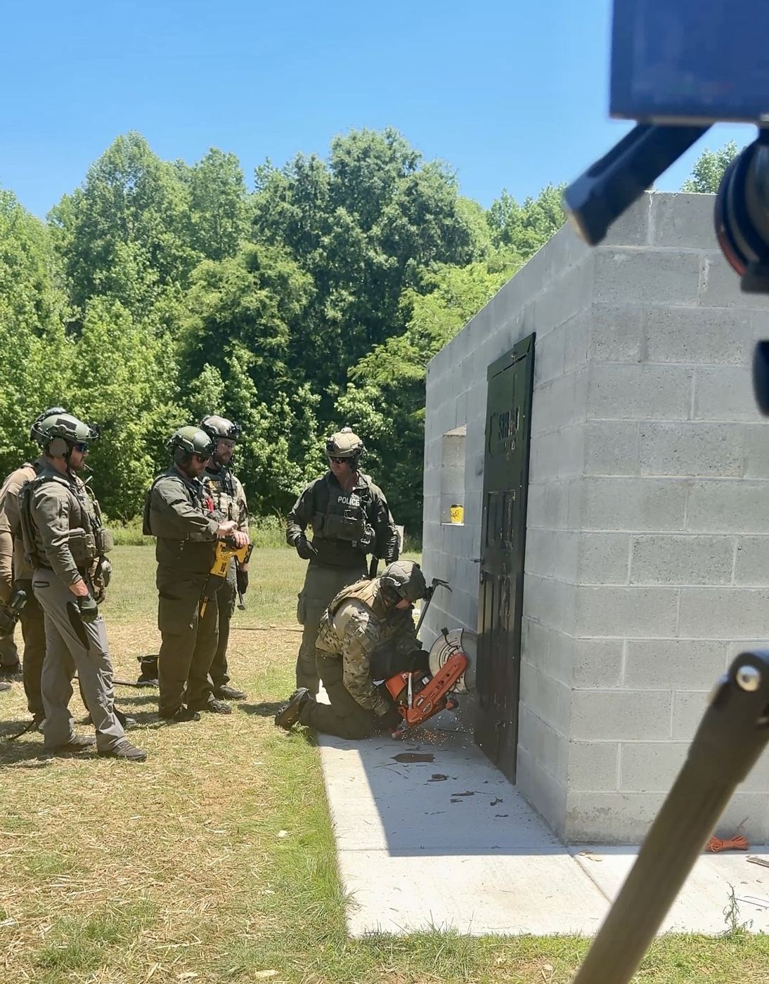 Officers working a breaching tool against a Shield door